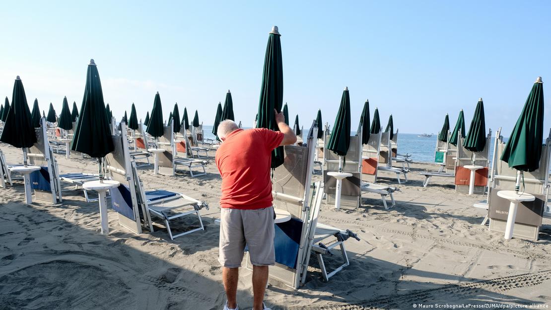 Ιδιοκτήτης beach bar τακτοποιεί τις ξαπλώστρες σε ιταλική παραλία Ιδιοκτήτης beach bar τακτοποιεί τις ξαπλώστρες σε ιταλική παραλία