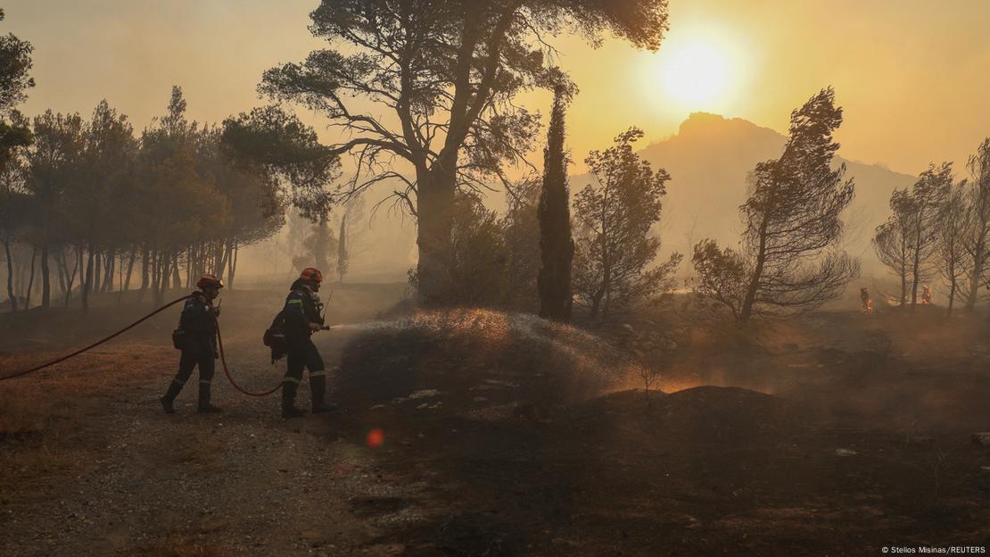 Bomberos tratan de apagar las llamas de incendios forestales cerca de Atenas.