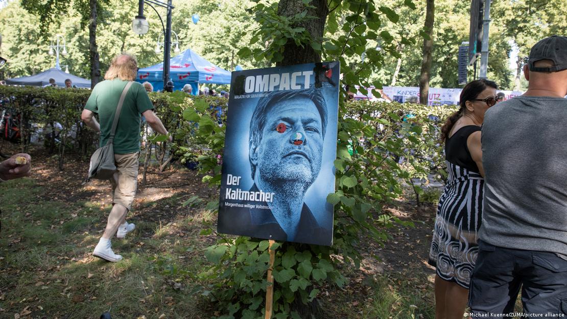 A placard in a Berlin park showing a Compact front page, featuring the face of Economy Minister Robert Habeck with damage to his eye end nose