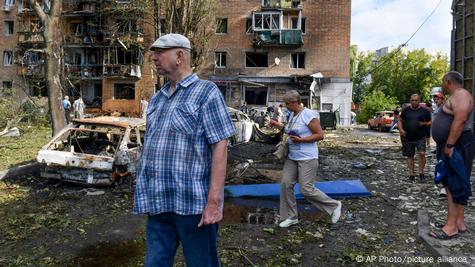 Personas caminan entre vehículos incendiados y un edificio destruido en Kursk, región rusa fronteriza con Ucrania.