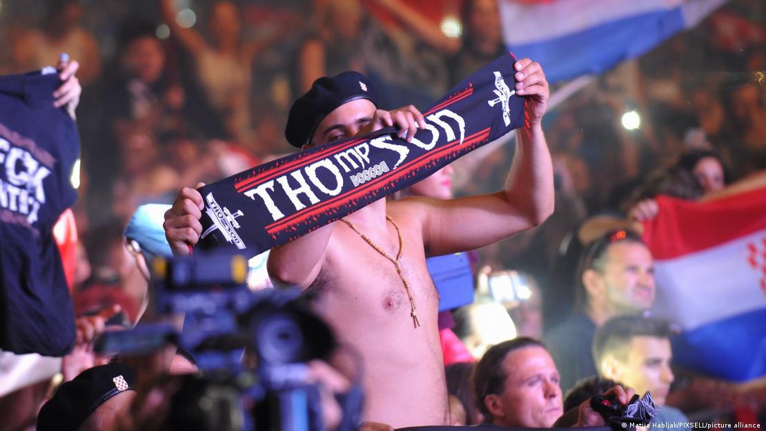 Publika na koncertu i jedan mladić golog trupa i crne beretke na glavi koji se ističe sa šalom na kojemu piše "Thompson"