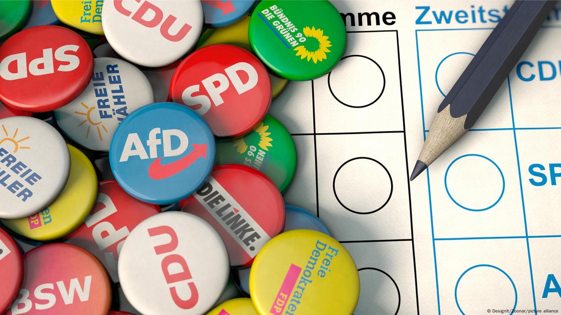 Ansteck-Buttons der verschiedenen Parteien in Deutschland und ein Stift liegen auf einem Wahlzettel