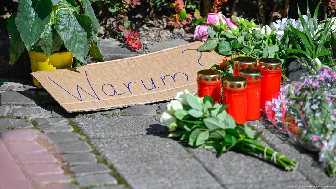 民众在案发地点附近放上鲜花蜡烛悼念死者，地上还放了一张写着“为社么？”的纸板