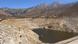 Ein großes Staubecken in den Bergen, das nur noch wenig Wasser enthält Ein großes Staubecken in den Bergen, das nur noch wenig Wasser enthält