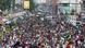 A massive crowd of people march in protest, many waving Bangladeshi and Palestinian flags, in the streets of Dhakar, Bangladesh