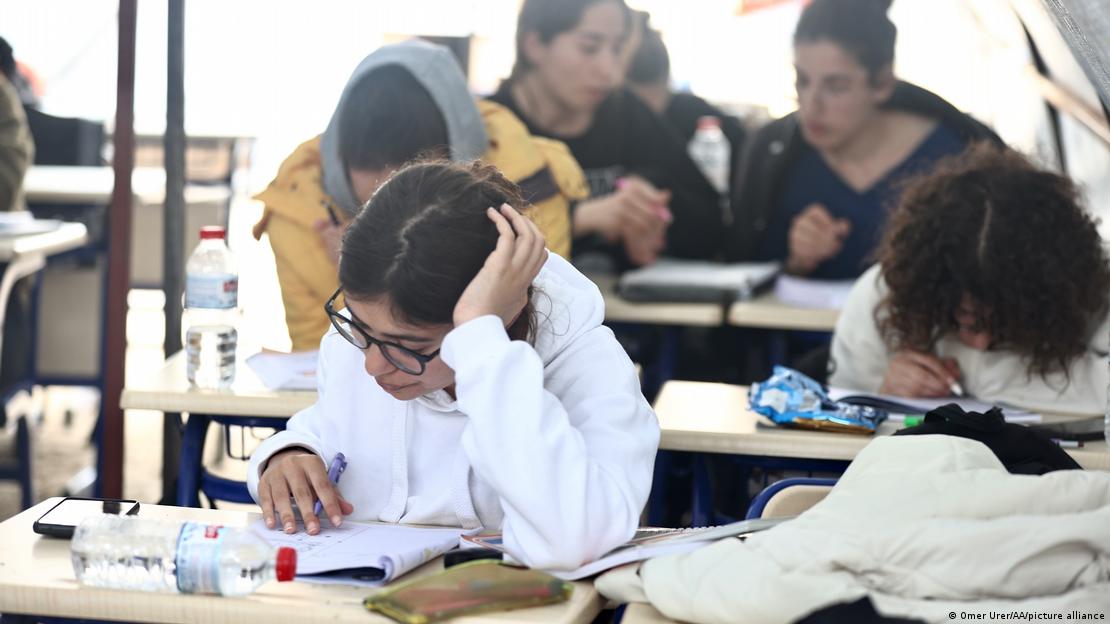 Bir derste öğrenciler sırada ders kitaplarına bakıyor. Bir derste öğrenciler sırada ders kitaplarına bakıyor.