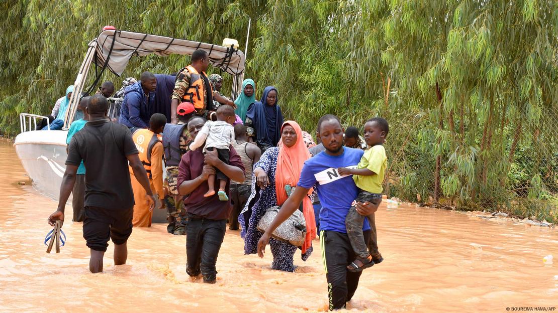 Personas huyen de zonas inundadas en Nigeria en bote, con niños en brazos. Personas huyen de zonas inundadas en Nigeria en bote, con niños en brazos.