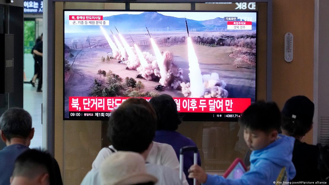 Pessoas em uma área pública acompanham notícia na TV de teste de míssil norte-coreano