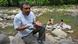 Juan Lopez sits on a rock beside the Guapinol river Juan Lopez sits on a rock beside the Guapinol river