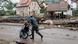 A man in waders pushes a woman in a wheelchair past a building destroyed by the floods in Ladek-Zdroj, southern Poland, September 16, 2024. A man in waders pushes a woman in a wheelchair past a building destroyed by the floods in Ladek-Zdroj, southern Poland, September 16, 2024.