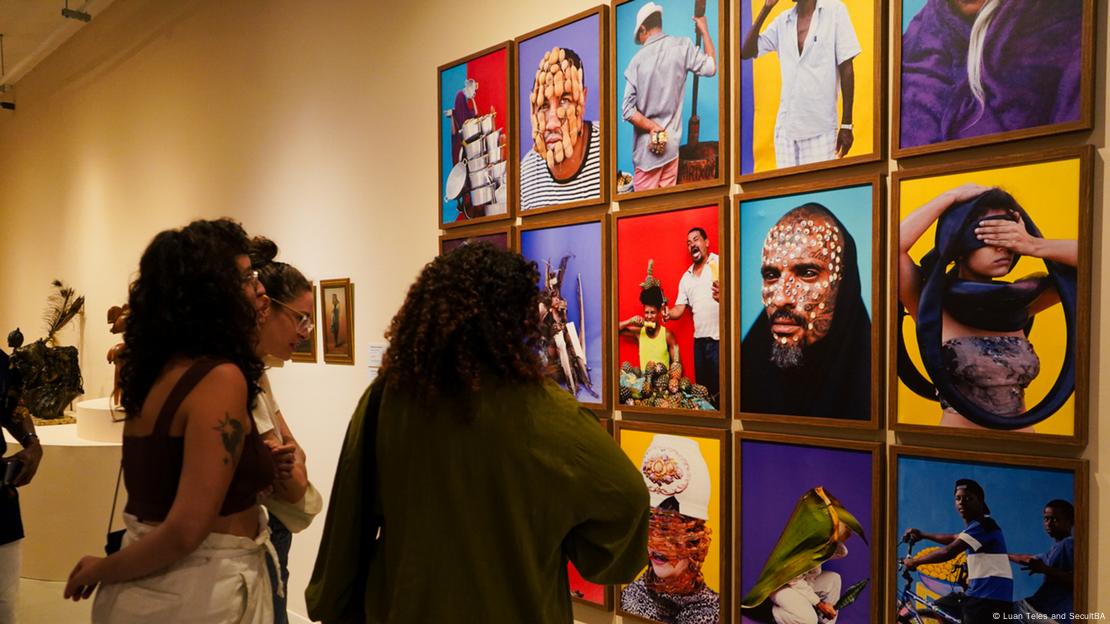 Mulheres olham obras em exposição no Muncab