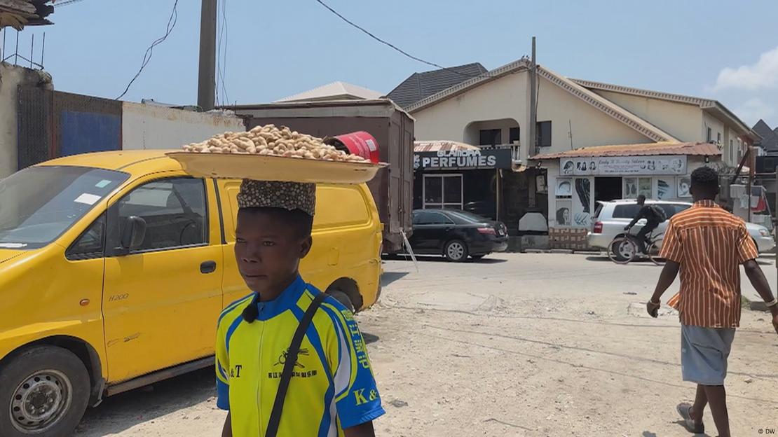 Criança carrega um prato com ingrediente para vender em rua em Lagos 