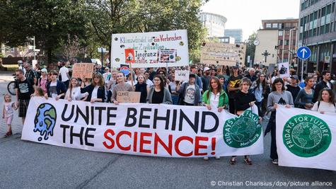 Protesters march behind a banner reading 'unite behind the science' Protesters march behind a banner reading 'unite behind the science'