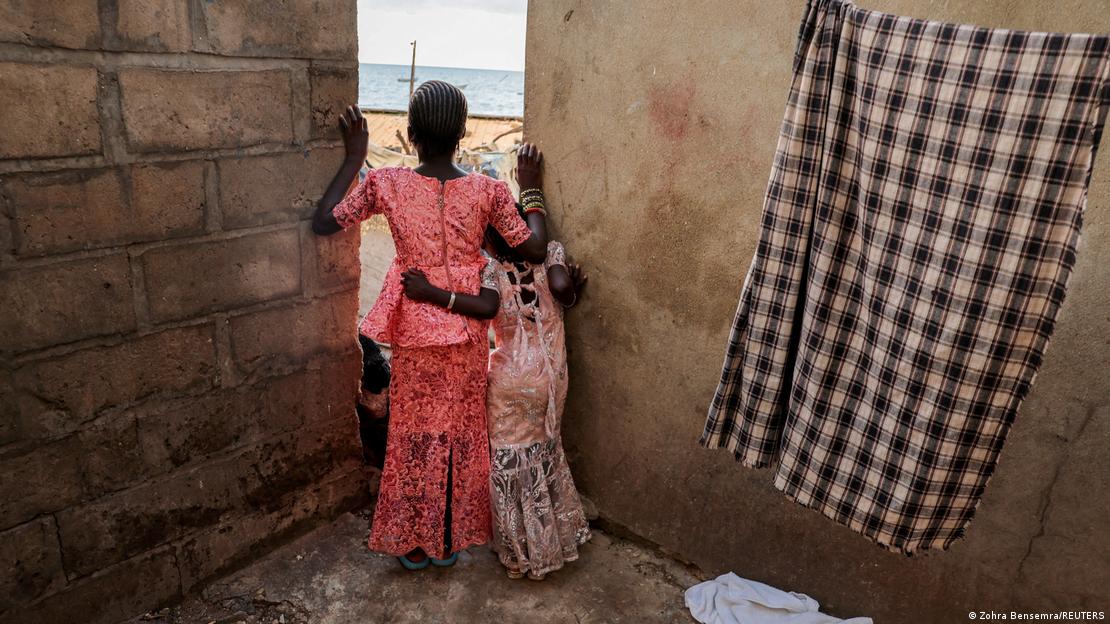 Deux petites filles de dos regardent la plage par le trou entre deux murs à Toubab Dialaw, Senegal (illustration de 2024)