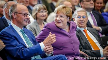 Friedrich Merz (left) and Angela Merkel (center) smile during a celebration of Merkel's 70th birthday