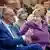 Friedrich Merz (left) and Angela Merkel (center) smile during a celebration of Merkel's 70th birthday