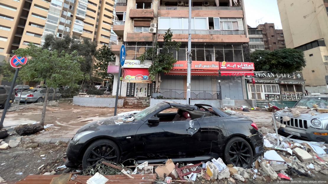 Carros danificados estacionados em meio a entulhos de bombardeio a prédio