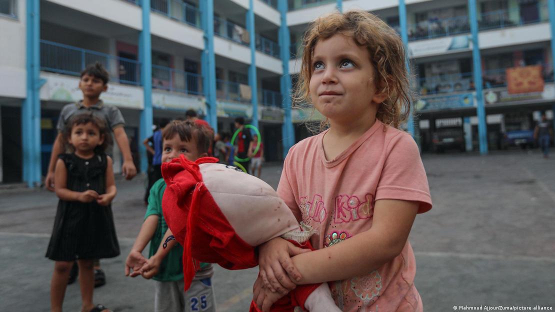 Gazze'de hayatta kalmak için okula sığınan bir kız çocuğu elinde oyuncak bir bebekle