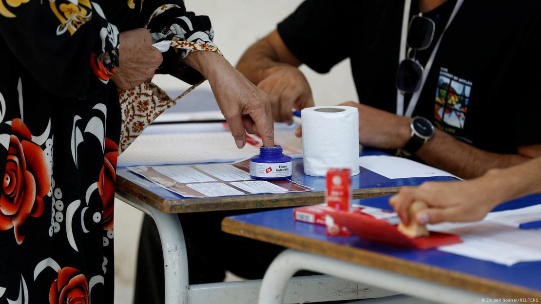 A woman has indelible ink applied to her finger as she votes at a polling station during the presidential election in Tunis, Tunisia October 6, 2024