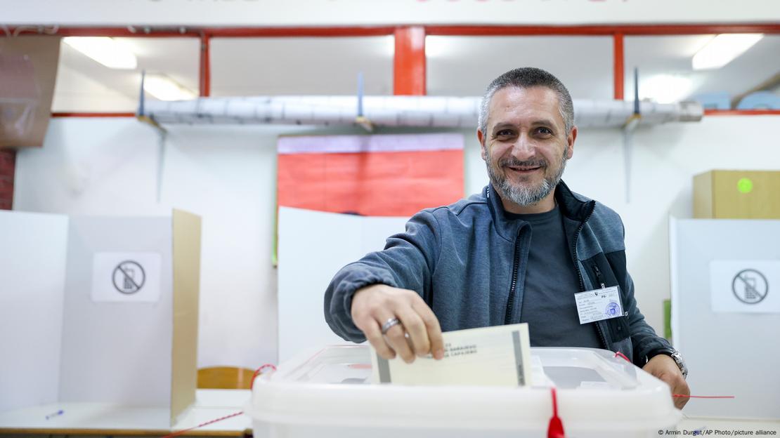 Sredovječni muškarac ubacuje glasački listić u kutiju