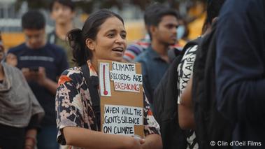 Rachita Taneja stands with a protest poster in a crowd