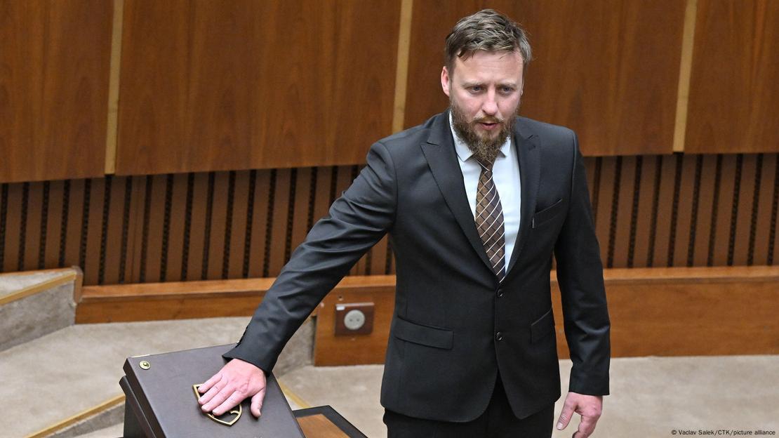 A man with a beard in a dark suit (MP Peter Kotlar) puts his hand on the constitution of Slovakia when he is sworn in in the Slovak parliament