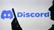 Человек смотрит на сматрфон на фоне логотипа Discord Человек смотрит на сматрфон на фоне логотипа Discord