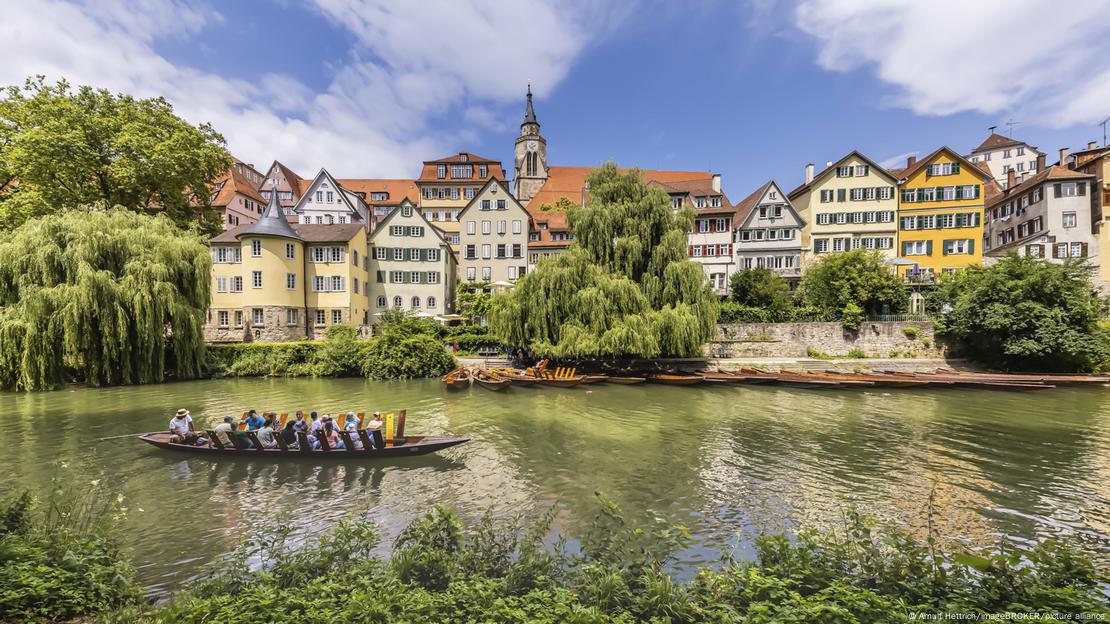 Pessoas em canoa no rio, com cidade de Tübingen ao fundo