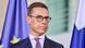 A man in glasses and a suit (Finland's President Alexander Stubb) stands in front of EU and Finnish flags A man in glasses and a suit (Finland's President Alexander Stubb) stands in front of EU and Finnish flags