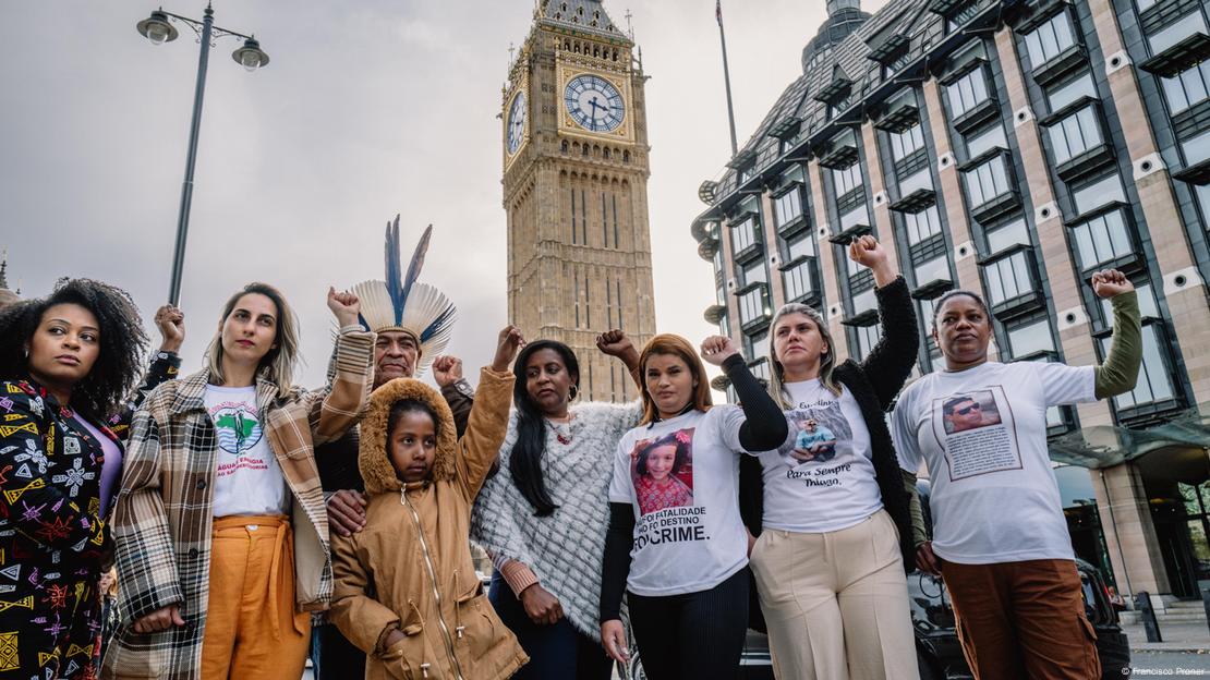 Oito pessoas erguem os punhos diante do Big Ben, em Londres, para protestar contra as empresas responsáveis pelo desastre de Mariana