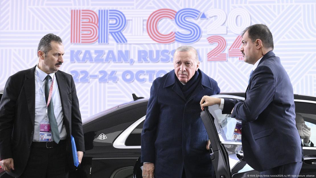 El presidente turco, Recep Tayyip Erdogan, llega a la cumbre de los BRICS en Kazán, Rusia, el 24 de octubre de 2024. El personal de seguridad abre la puerta de su vehículo oficial mientras al fondo se puede ver el logo de la cumbre. El presidente turco, Recep Tayyip Erdogan, llega a la cumbre de los BRICS en Kazán, Rusia, el 24 de octubre de 2024. El personal de seguridad abre la puerta de su vehículo oficial mientras al fondo se puede ver el logo de la cumbre.