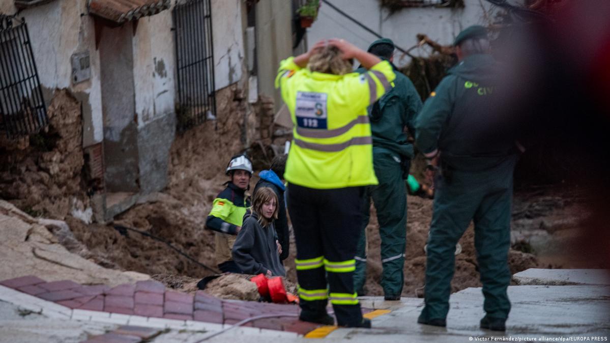 Una rescatista, de espaldas, levanta las manos y se las lleva a la cabeza, ante la magnitud de los daños de las inundaciones que observa.