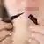 Symbolic image of a young woman holding a pencil eyeliner close to the camera, with no brand name visible. Taken in Hamburg in 2017.