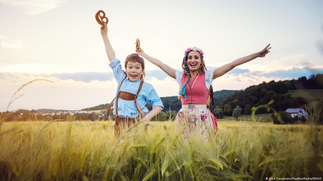Imagen simbólica de un niño y una joven felices, saltando con un bretzel en la mano, sobre la hierba.