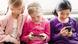 Three young children looking at smartphones Three young children looking at smartphones