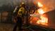 A firefighter in protective gear directs a blast of water at flames engulfing a shed A firefighter in protective gear directs a blast of water at flames engulfing a shed