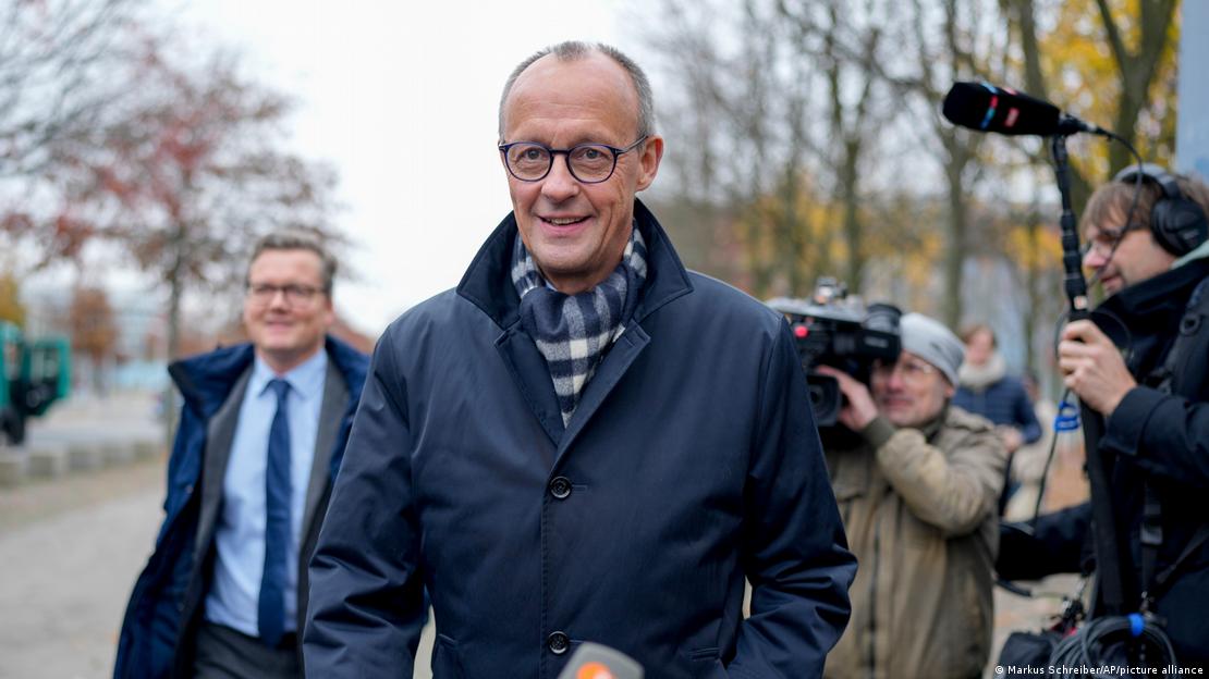 Kreu i CDU, Friedrich Merz duke shkuar në takim me kancelarin Scholz, Merz para kamerave, veshur me xhaketë blu e shall me kuadrate blu e të bardhë