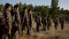 Irak | Guerrileros del PKK caminan en fila por el campo.