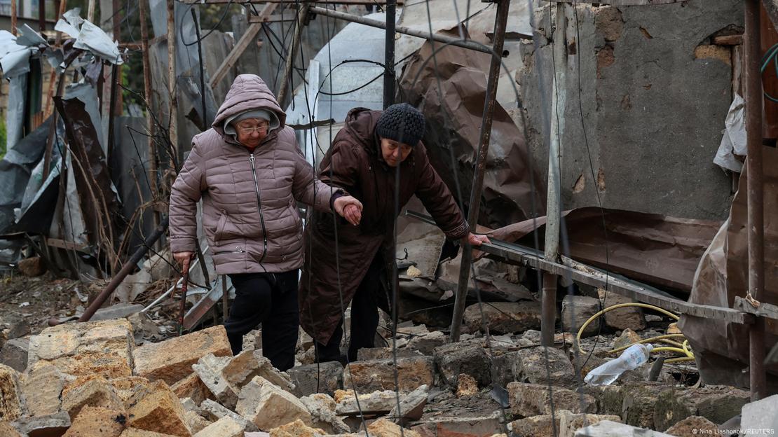 Rusya'nın Odessa'ya düzenlediği İHA saldırıları sonucunda yok edilen bir bina, önünde yürüyen insanlar