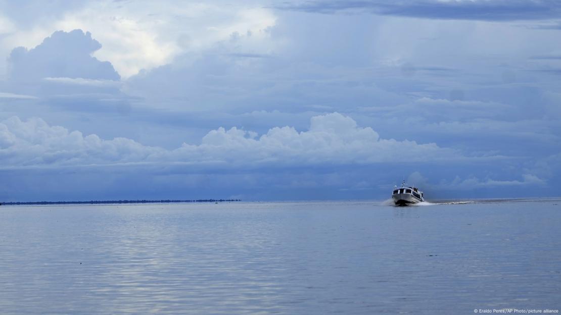 Barco navega em águas calmas, com nuvens no horizonte