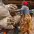 Nigerian woman stacks large bags of cassava plants