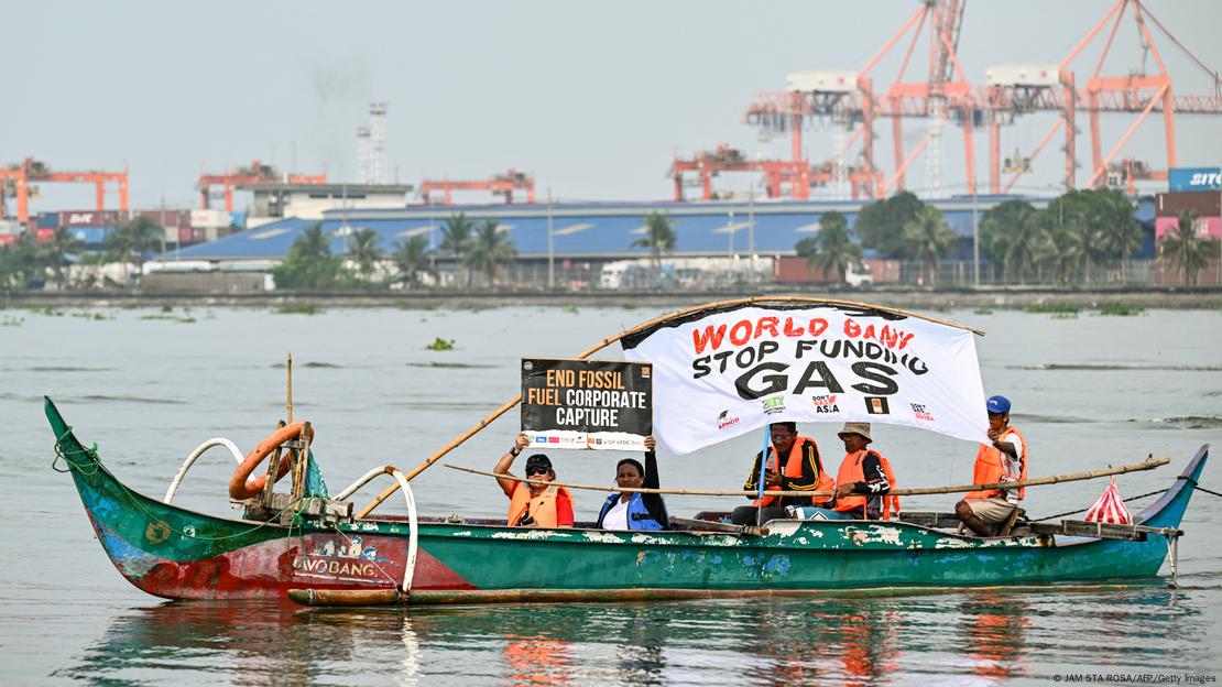 Umweltschützer halten auf einem kleinen Boot, das vor Hafenanlagen im Wasser treibt, ein Plakat in die Höhe; darauf steht: "Stop funding Gas"