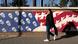Mulher em Teerã passava por mural representando bandeira dos Estados Unidos com caveiras no lugar de estrelas, e soldados armados enfileirados nas listras vermelha e branca Mulher em Teerã passava por mural representando bandeira dos Estados Unidos com caveiras no lugar de estrelas, e soldados armados enfileirados nas listras vermelha e branca