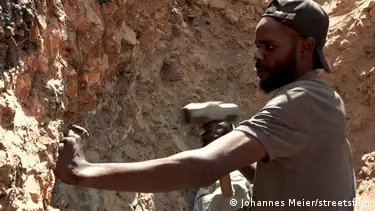 Miner Paul Gazabe Nbanze hammers a rock in a small-scale mine.