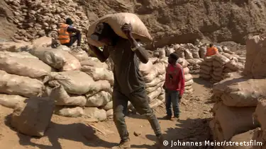 Miners in the Congo carry sacks of ore
