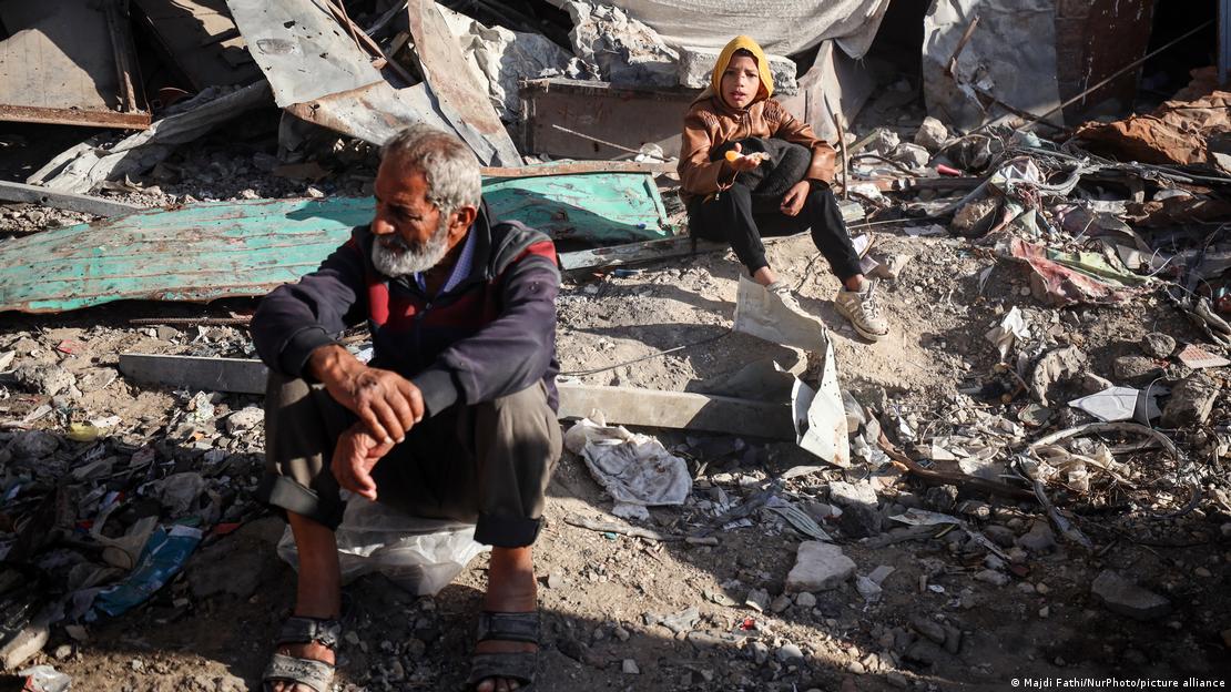 Un hombre y un niño sentados entre ruinas y escombros de edificios en Jan Yunis, en la Franja de Gaza.