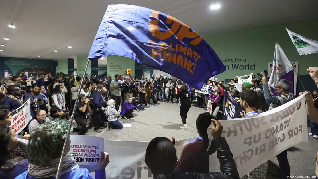 Demonstrierende Menschen schwenken in einem Saal Protest-Banner auf der UN-Klimakonferenz COP29 in Baku in Aserbaidschan 