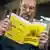 A man holds a yellow brochure titled "If the crisis or war comes" in Swedish