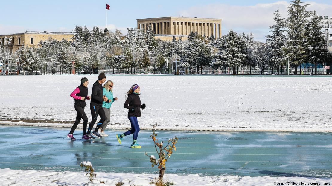 Bu fotoğrafta 4 kişi sokakta karlı bir havada koşuyor