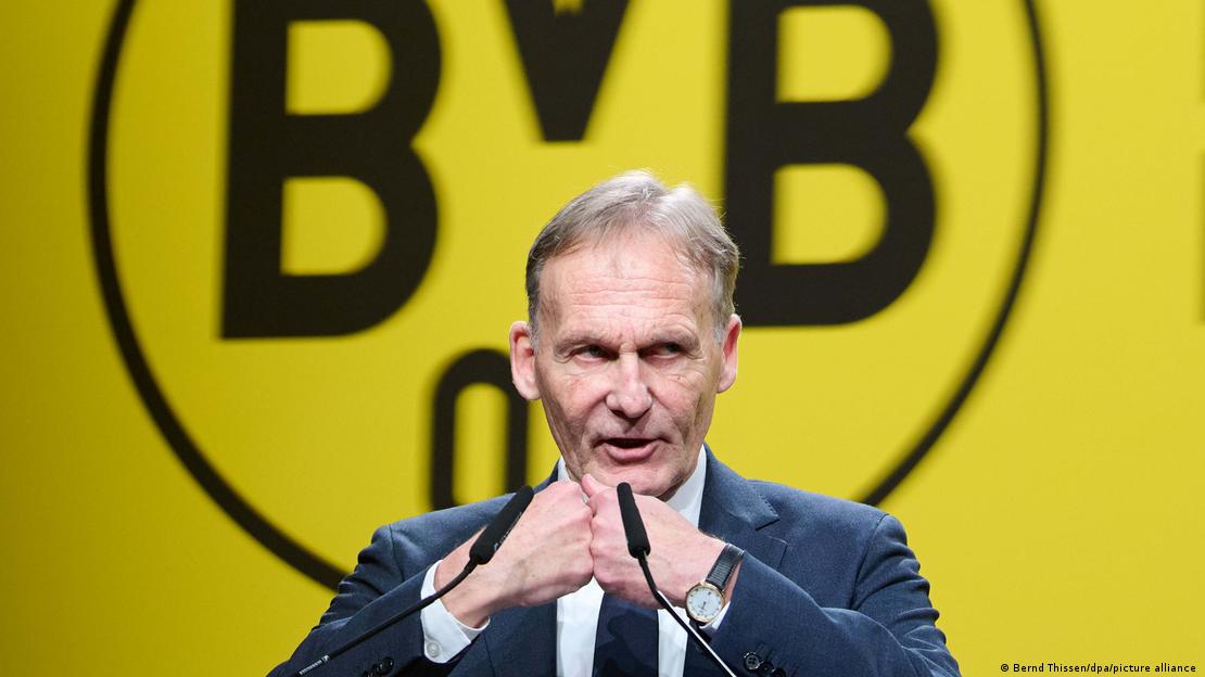 UEFA İcra Komitesi Başkan Yardımcısı ve Borussia Dortmund Başkanı Hans-Joachim Watzke, büyük bir Borussia Dortmund logosu önünde konuşma yapıyor